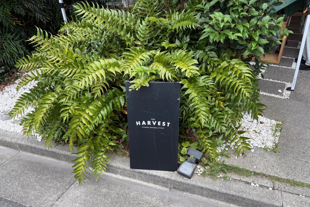 恵比寿の緑の茂みに置かれたTHE HARVEST KITCHEN GENERAL STOREの看板