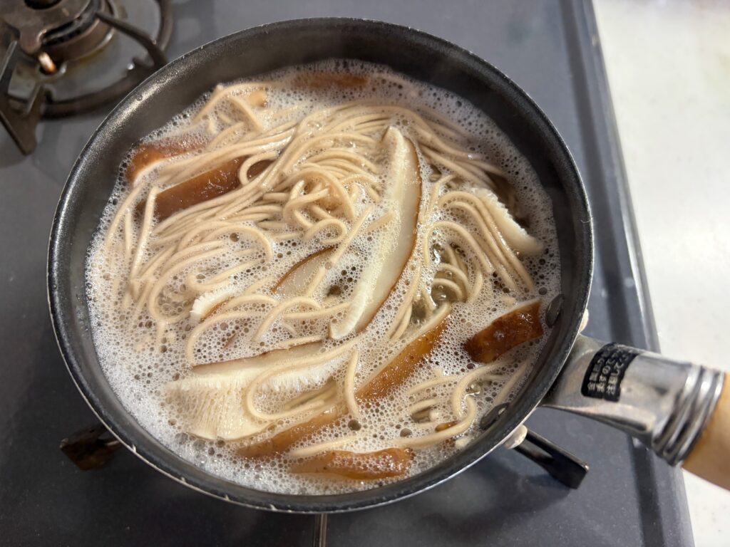 小鍋でそばとしいたけを一緒に煮ているところ