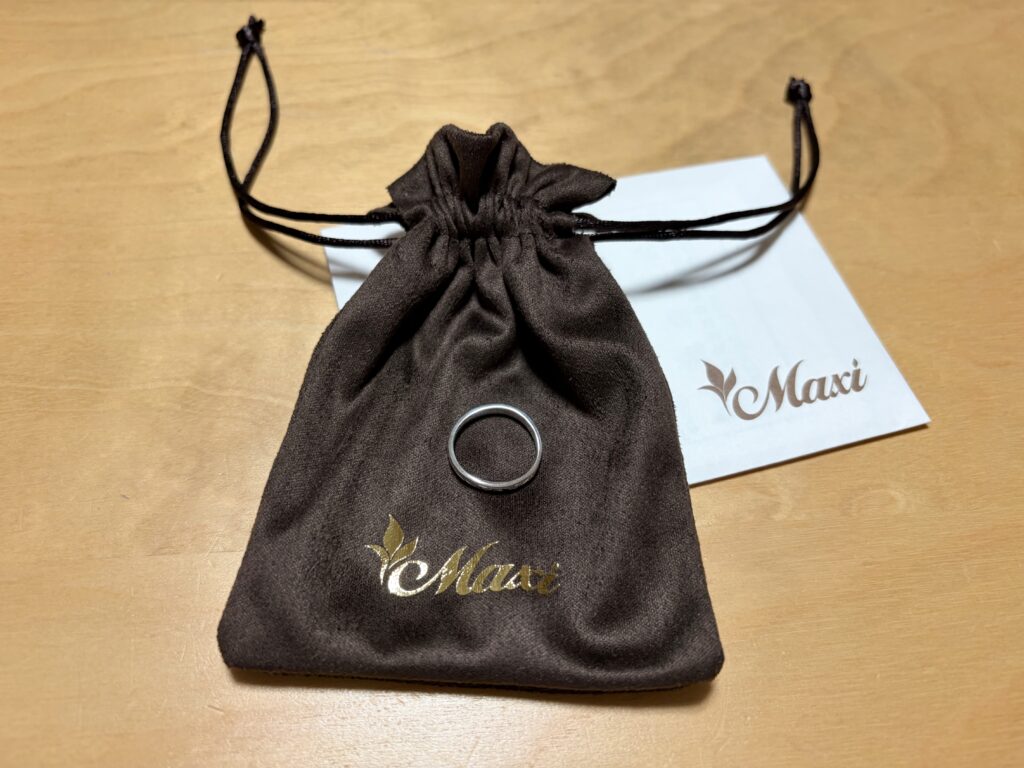 Maxiの巾着袋の上に置かれたリングとブランドカード