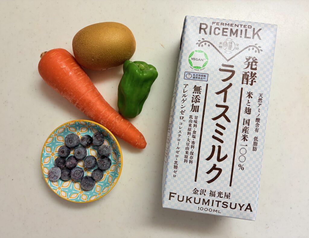 ゴールドキウイ、にんじん、ピーマン、小皿に盛った冷凍ブルーベリー、福光屋の発酵ライスミルクのパック